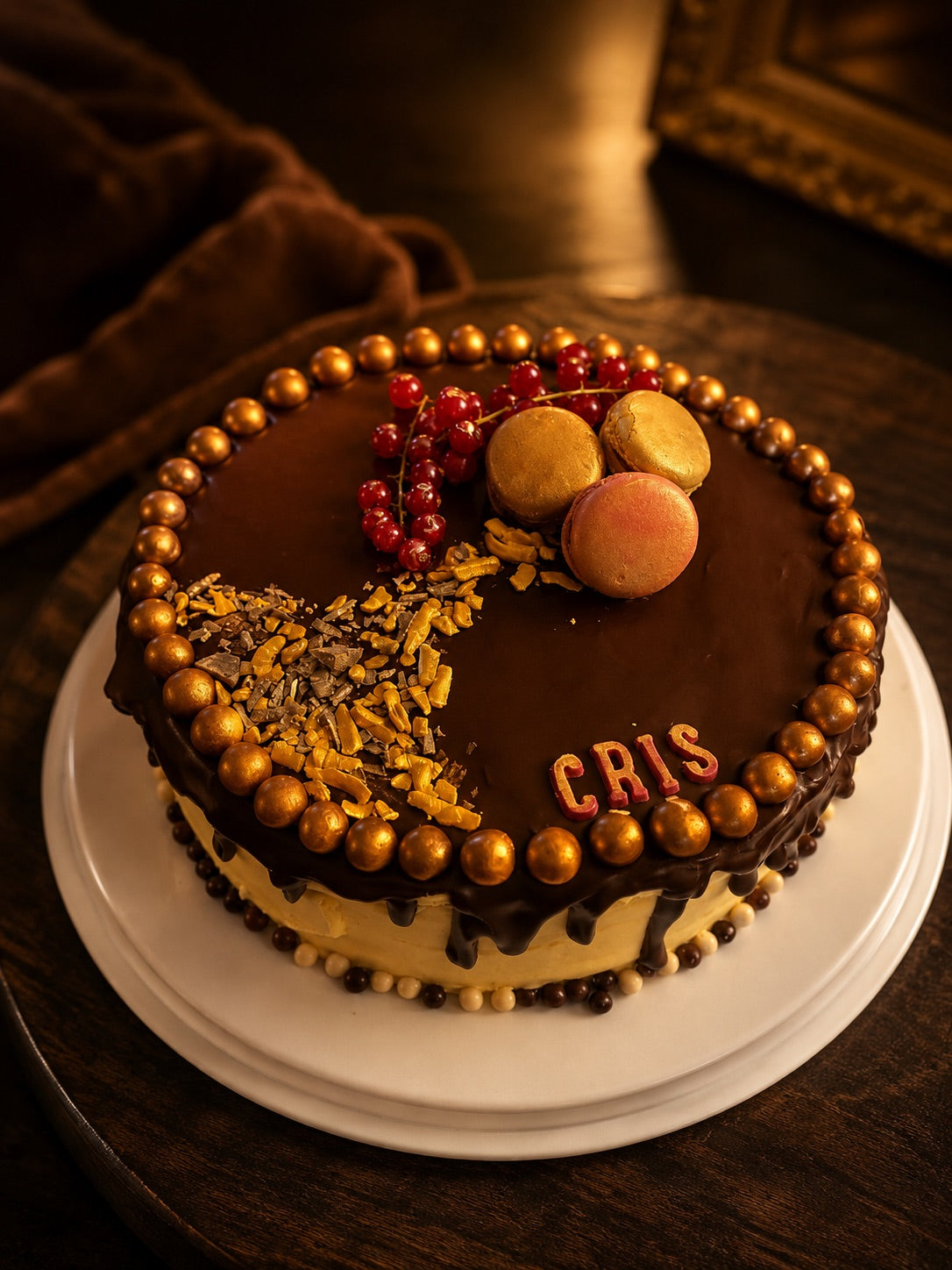 Chocolade-ganachetaart met gouden parels, macarons en rode bessen